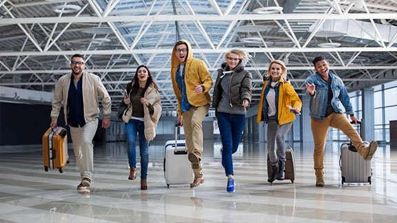 Group of travellers walking through an airport terminal with luggage