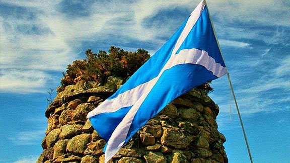 Scottish Saltire flag flying above a rocky Highland landscape
