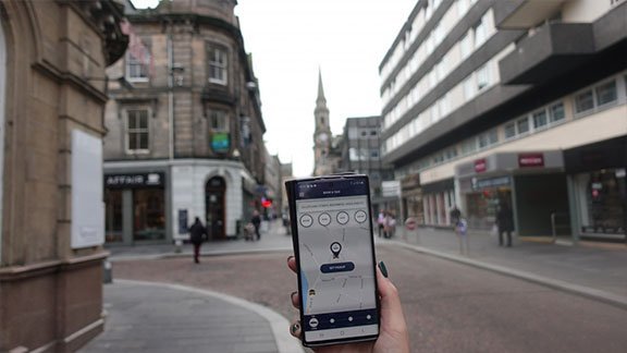 Inverness Taxis booking app displayed on a phone in Inverness city centre