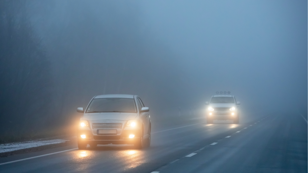 Cars with headlights on travelling along a foggy road