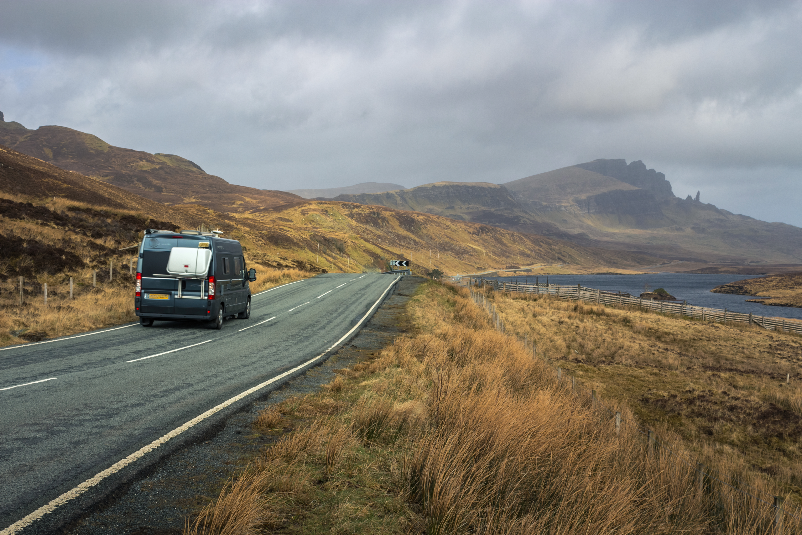 Vehicles travelling along a winding road through the hills of the Isle of Skye